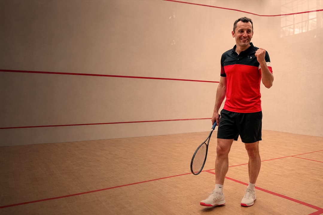 Un joueur souriant, poing levé, sur un court du club